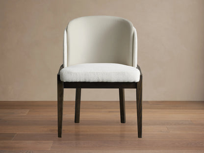 Front view of the Mena Dining Chair with a solid ash wood frame in dark finish. Upholstered in beige faux leather with a softly curved backrest and cushioned seat.
