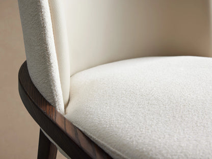Mena Dining Chair close-up showing beige seat cushion and smooth backrest, with dark wood frame visible on the side.