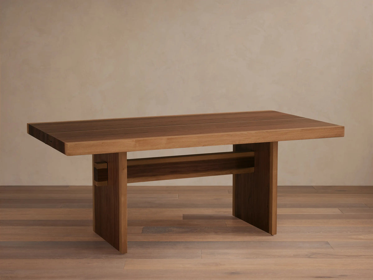 Mihaela Dining Table made from Romanian oak and spruce with walnut veneer. Features a sleek rectangular top and unique cross-beam legs on wooden floor.