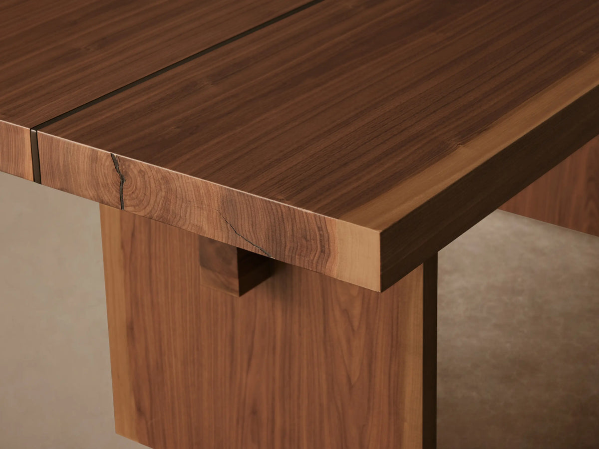 Mihaela Dining Table in a Walnut finish, featuring a rectangular top with visible wood grain, supported by two parallel plank legs and a horizontal crossbar.