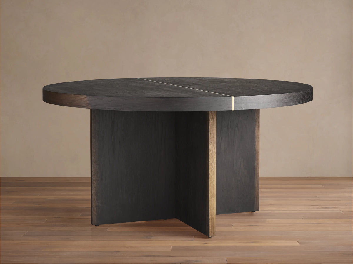 Mihaela Round Dining Table, dark wood with visible grain & brass accent line. Angled view of round top & cross-shaped base.