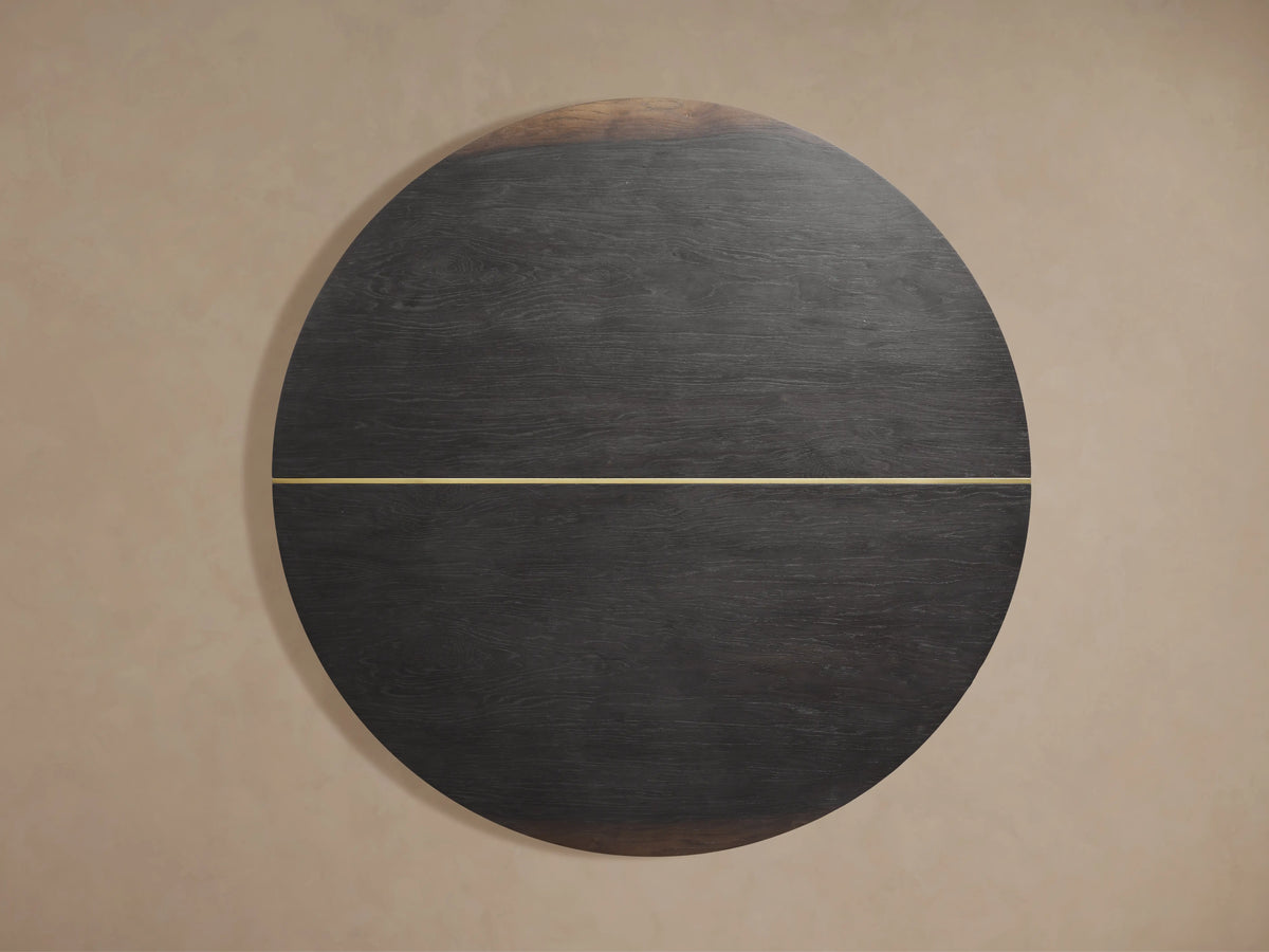 Mihaela Round Dining Table with a dark walnut wood top, showing subtle sheen and a brass inlay across its surface and side.