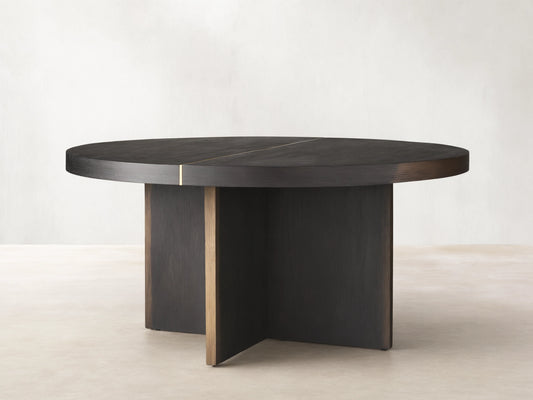 Mihaela Round Dining Table, dark wood with visible grain & brass accent line. Angled view of round top & cross-shaped base.
