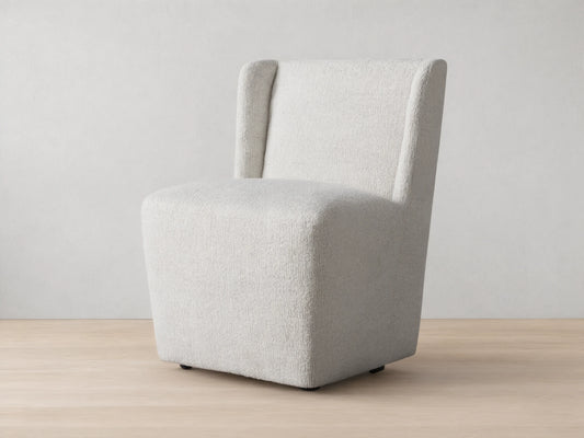 Mila Dining Chair with light beige fabric, featuring a sleek, armless design and subtle texture on wooden floor.