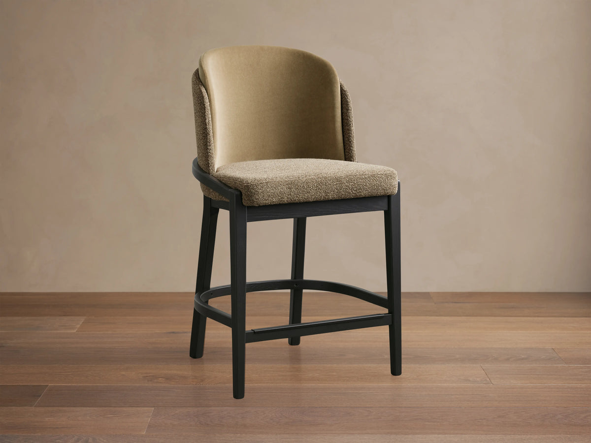 Mena Stool with beige faux leather backrest, taupe fabric seat, and black ash wood frame on wooden floor.