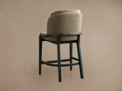 Mena Stool with beige faux leather backrest, taupe fabric seat, and black ash wood frame on wooden floor.
