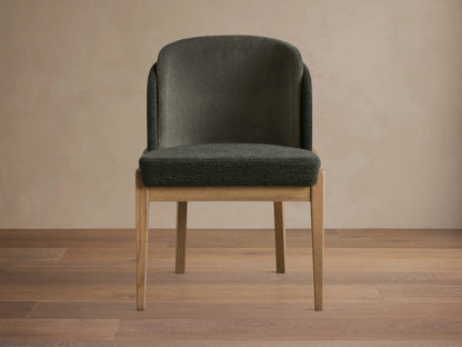 Mena Dining Chair with dark gray upholstery, featuring smooth backrest fabric and textured seat/trim. Light ash wood frame, tapered legs.