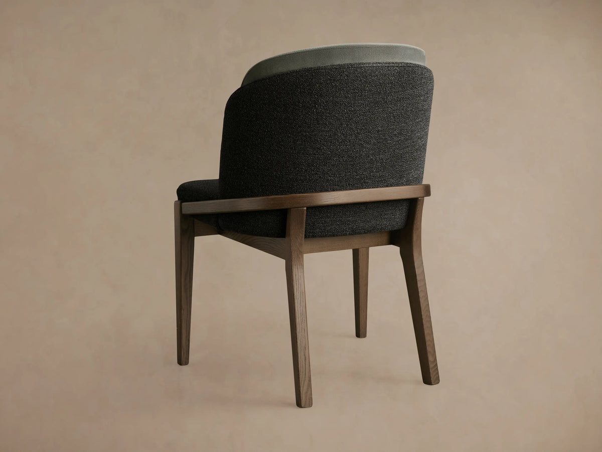 Mena Dining Chair with dark ash wood frame and layered backrest in charcoal and light grey fabric, viewed from back-left.