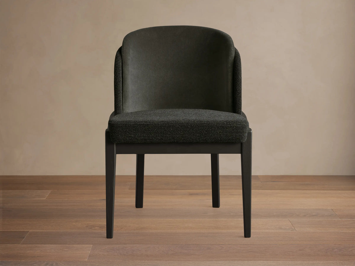 Dark charcoal gray Mena Dining Chair with curved back and black ash wood tapered legs, seen from the front.