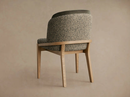 Close-up of Mena Dining Chair with light ash wood frame, speckled grey/beige fabric seat, and dark green inner backrest.