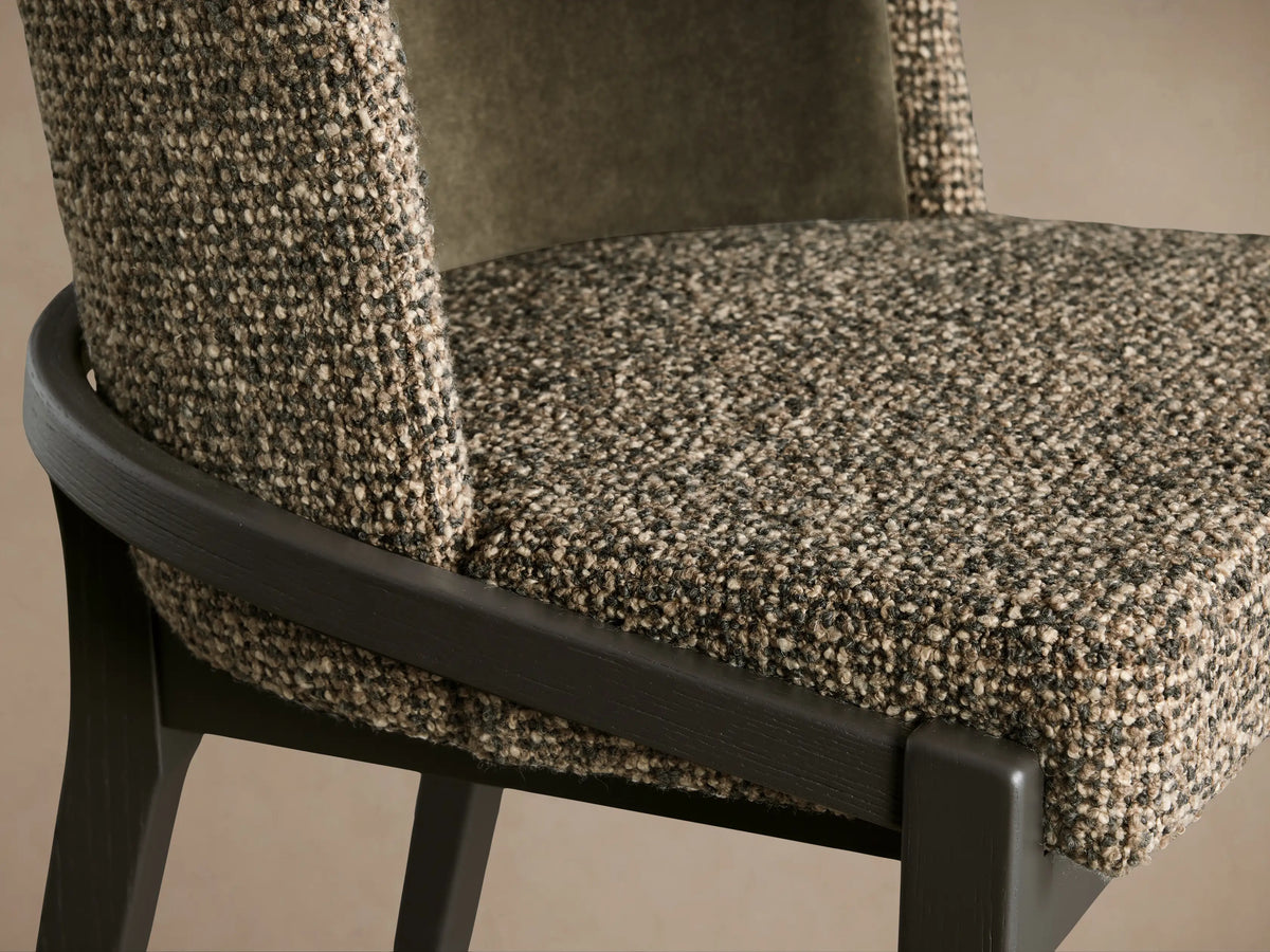 Close-up of Mena Dining Chair, showing multi-tone woven fabric seat & outer back, dark ash wood frame, and olive green inner backrest.