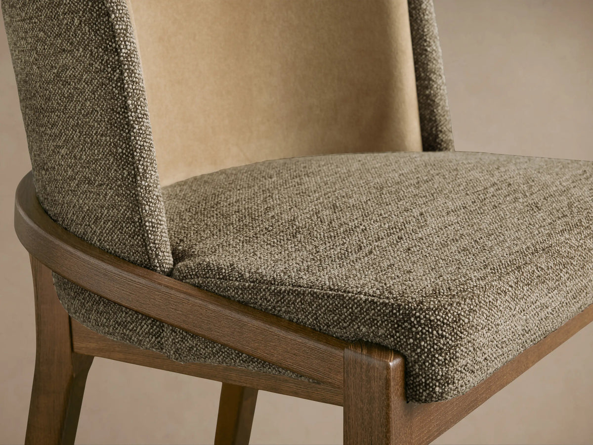 Mena Dining Chair. Close-up of layered backrest with textured brown and smooth beige fabrics, dark ash wood frame, curved detail.