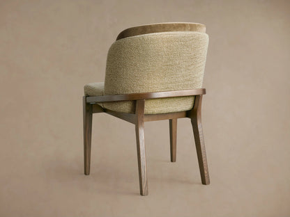 Mena Dining Chair, angled back. Dark ash wood frame, tapered legs. Layered backrest: textured light olive & smooth darker brown fabric.