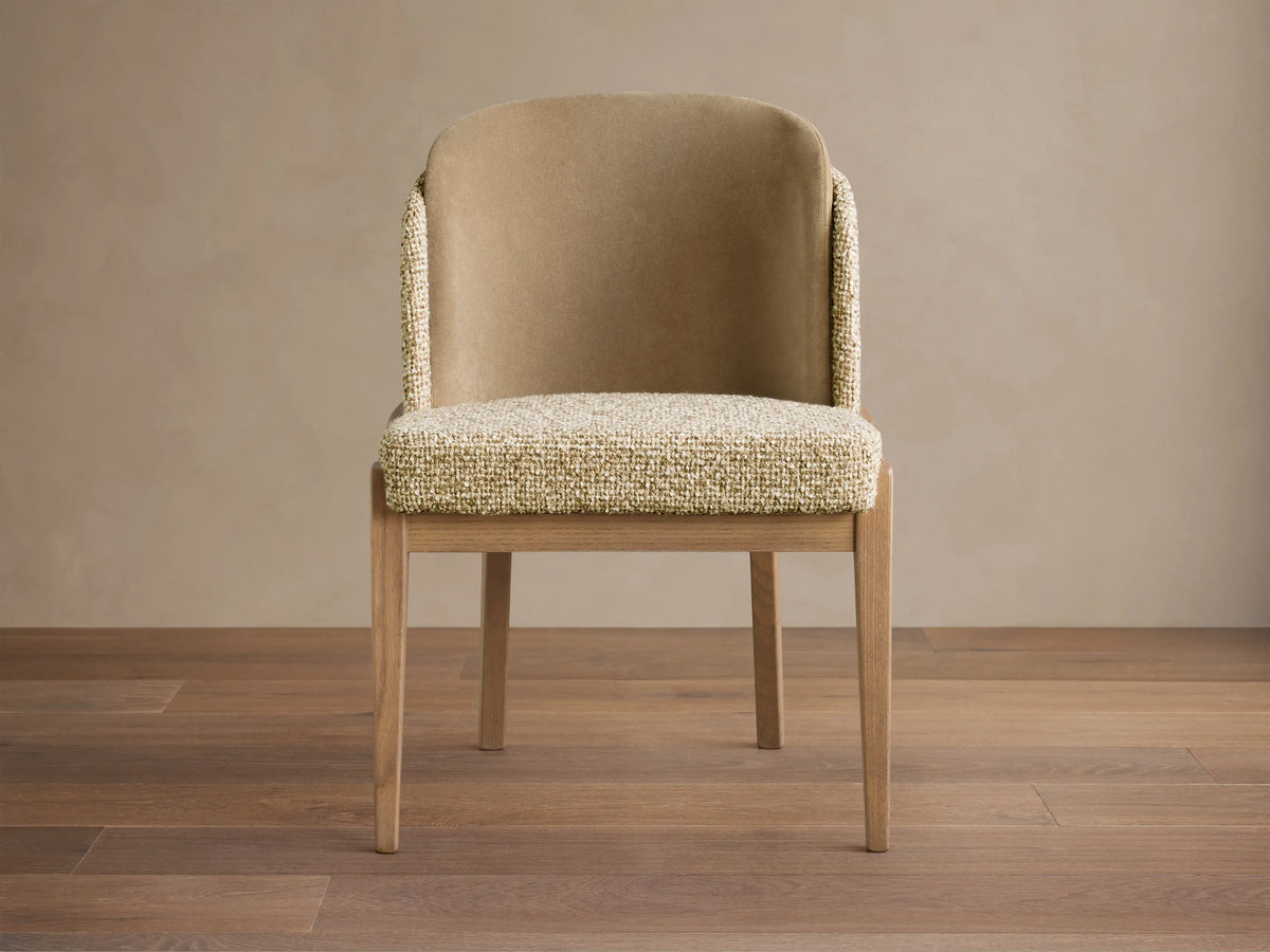 Mena Dining Chair, front view. Curved back, smooth beige, textured light speckled fabric on sides & seat. Tapered wood legs.