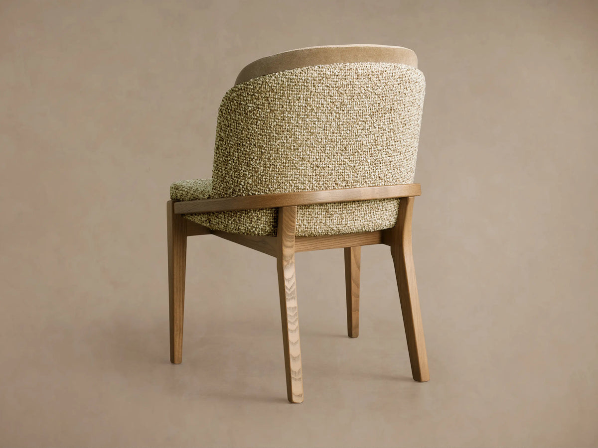 Mena Dining Chair, angled back. Curved back with green-beige textured fabric & light beige trim, on natural ash wood frame.