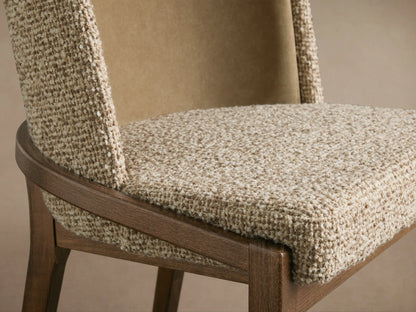 Close-up of Mena Dining Chair. Oatmeal textured fabric seat & front backrest, smooth tan inner back. Dark wood frame & legs.