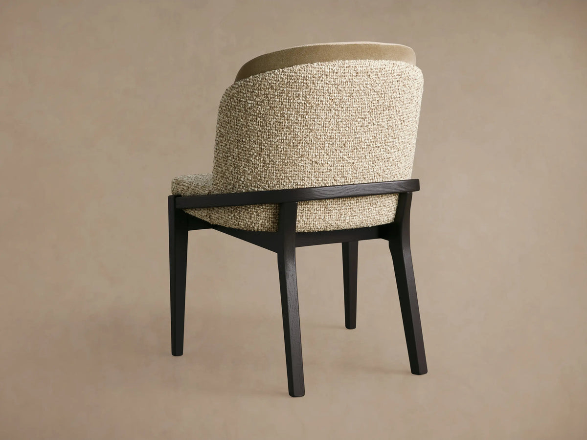 Mena Dining Chair, angled back view. Dark wood frame, textured beige upholstery with a lighter olive top back accent, curved back.