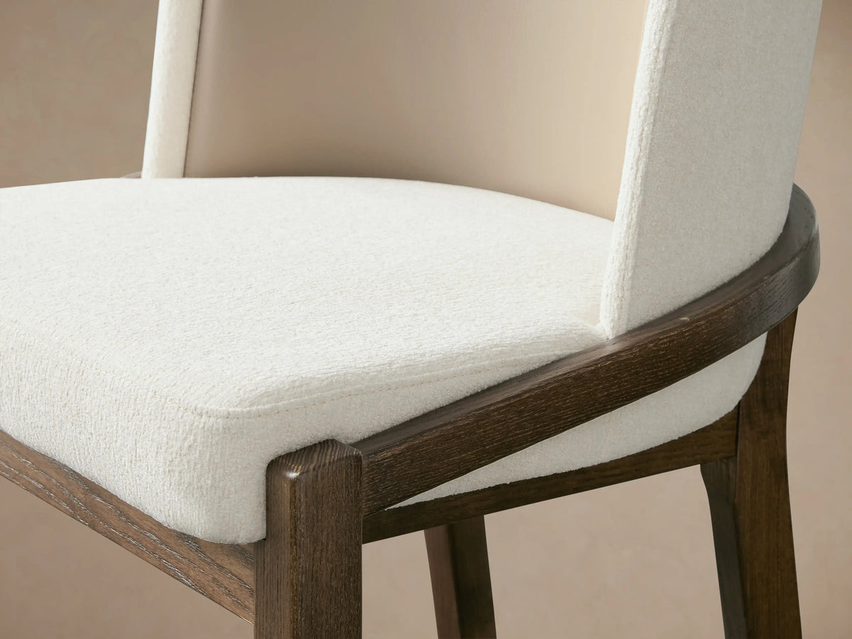 Mena Stool, front. Dark ash wood frame with tapered legs, curved back in beige & off-white fabrics, light seat.