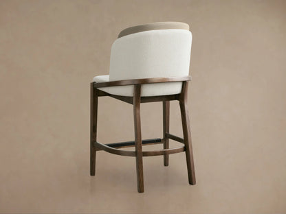 Close-up of Mena Stool with textured cream upholstered seat & back, smooth tan inner back, and elegant dark ash wood frame.