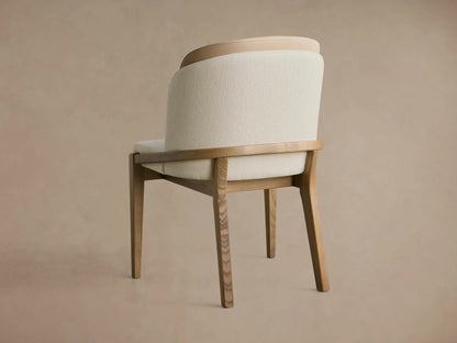 Mena Dining Chair, 3/4 back view. Cream fabric & light brown leather layered back, ash wood frame, tapered legs.
