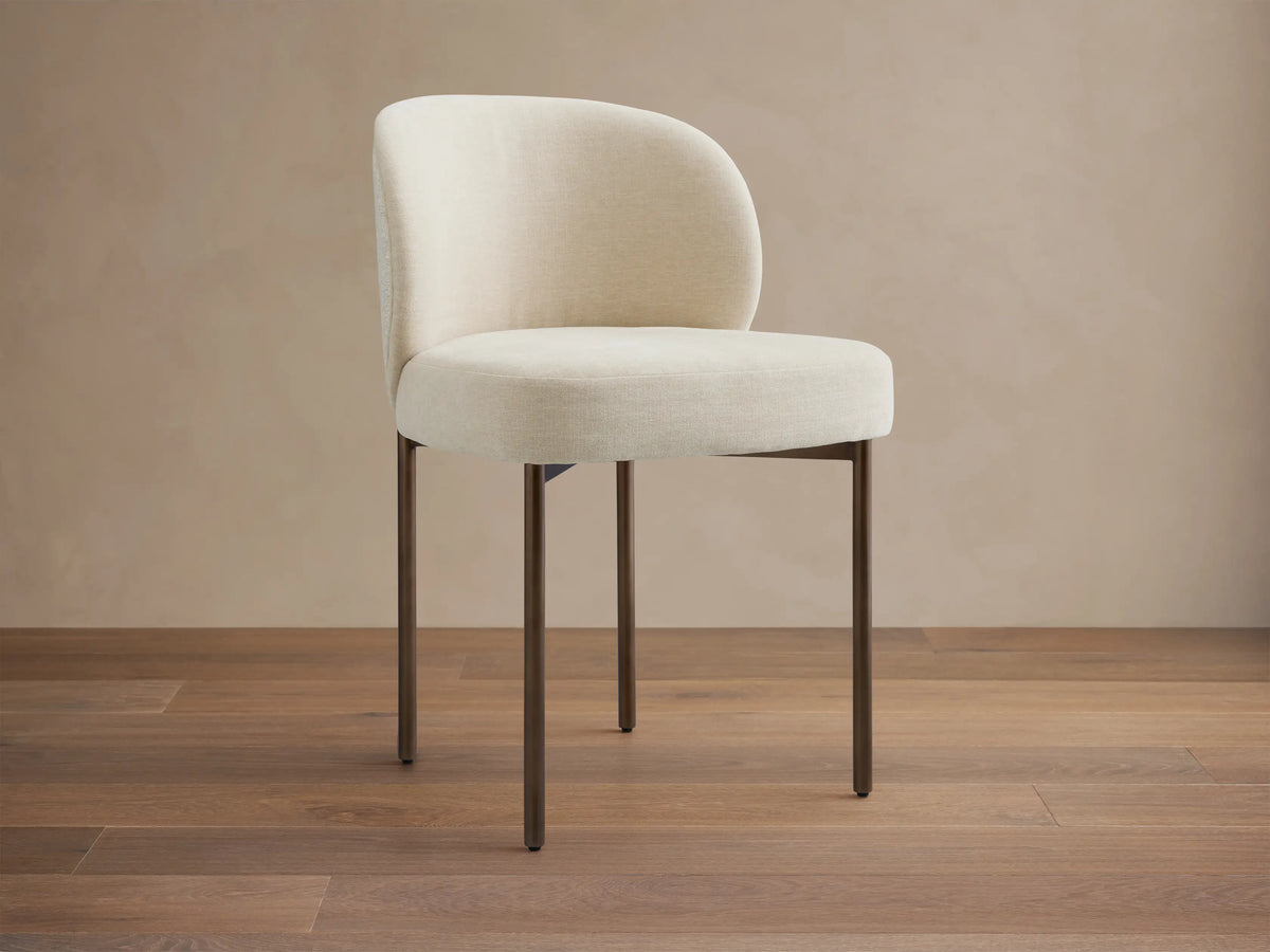 Myers Dining Chair featuring a cream upholstered seat and backrest with sleek, dark wooden legs, placed on a hardwood floor.