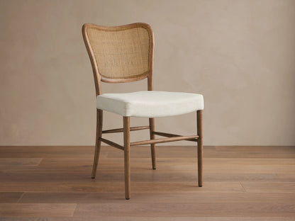 Noa Dining Chair with medium brown oak frame, curved woven rattan back, and cream fabric seat, viewed from front.