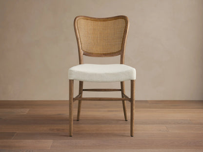 Noa Dining Chair with medium brown oak frame, curved woven rattan back, and cream fabric seat, viewed from front.