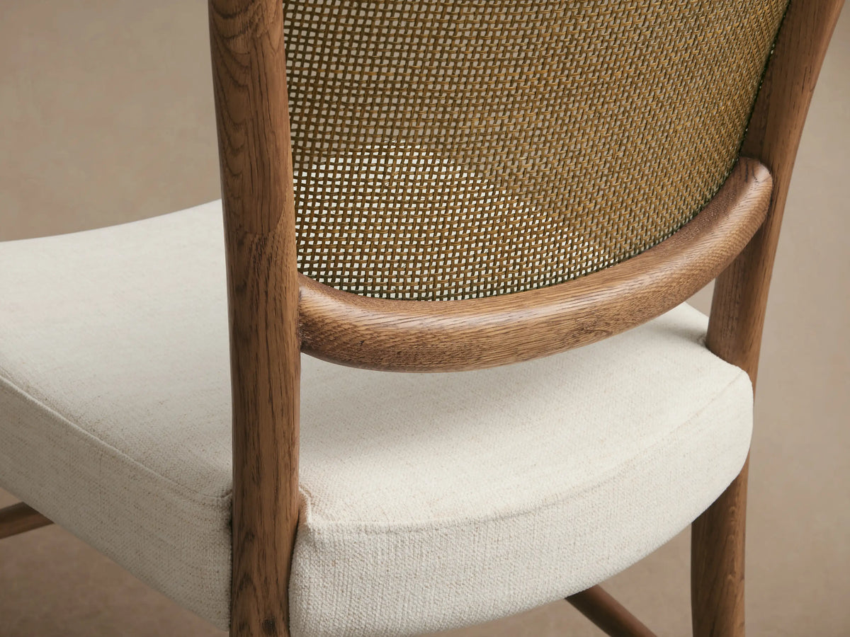 Noa Dining Chair with light brown oak frame, woven rattan backrest, and light fabric upholstered seat.