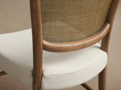 Noa Dining Chair with light brown oak frame, woven rattan backrest, and light fabric upholstered seat.