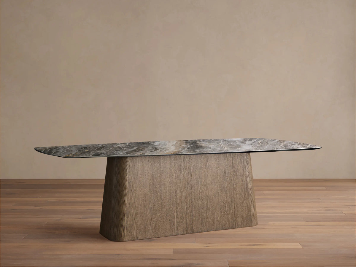 Vincenza Dining Table: grey marble-effect ceramic top with rounded corners on a textured light brown oak veneer pedestal base.