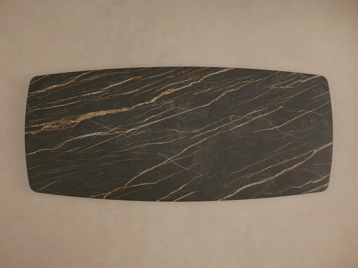 Close-up of the dark brown marble-patterned ceramic top and wavy steel base of the Ortenzia Dining Table.