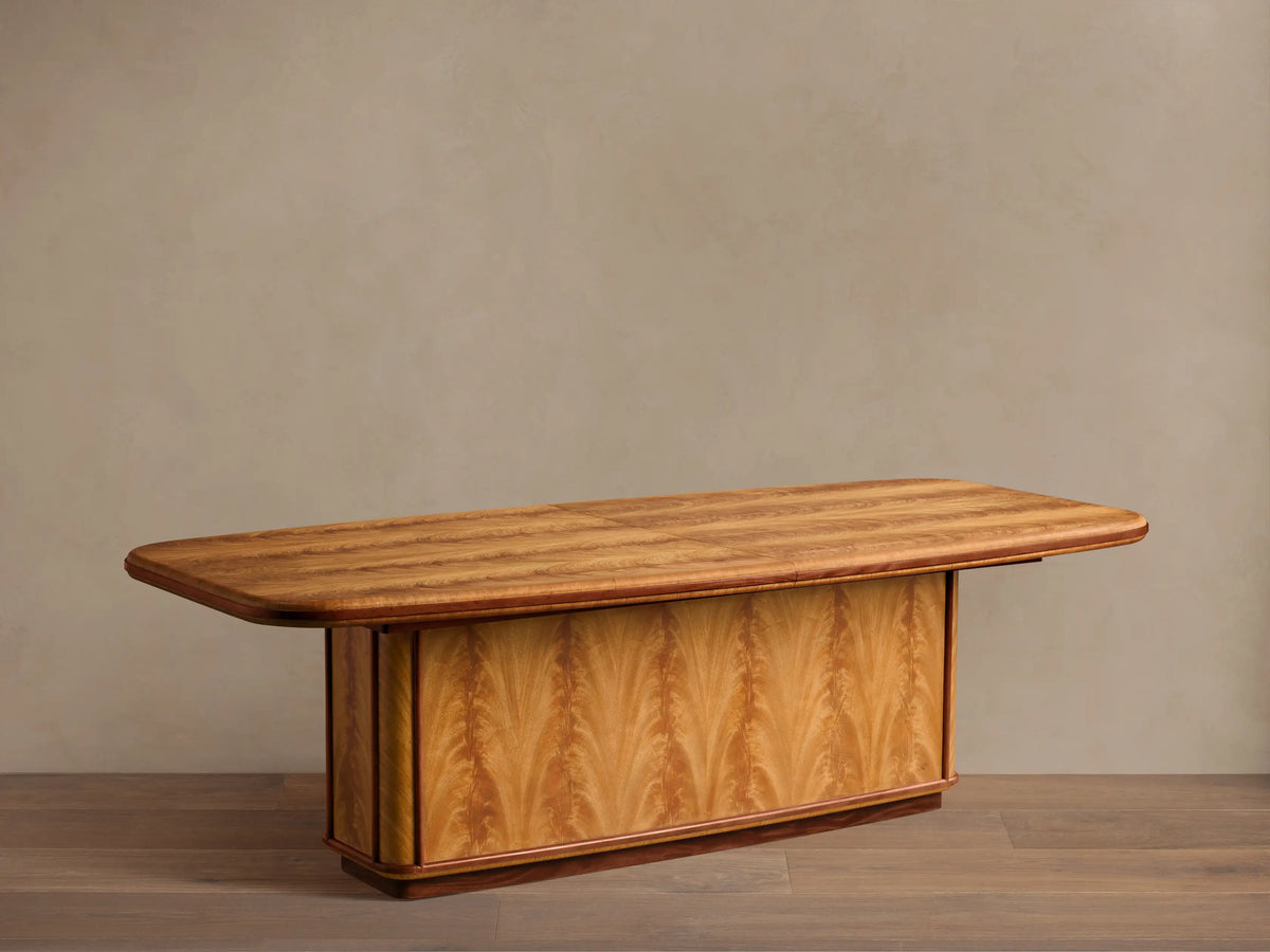 Front view of Palma Extension Dining Table, cerajeira wood veneer tabletop with striped graining, arched base, and dark primavera trim.