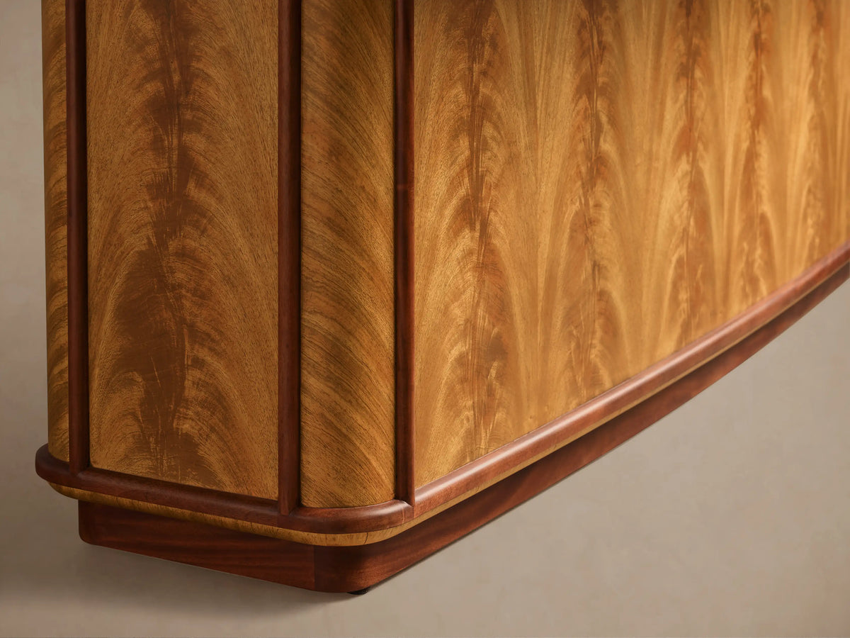 Close-up of the curved base of the Palma Extension Dining Table, showcasing cerajeira veneer with cathedral graining and dark trim.