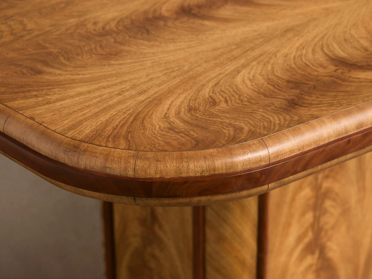 Close-up of the Palma Extension Dining Table's cerajeira wood veneer top with swirling grain and dark primavera edge trim.