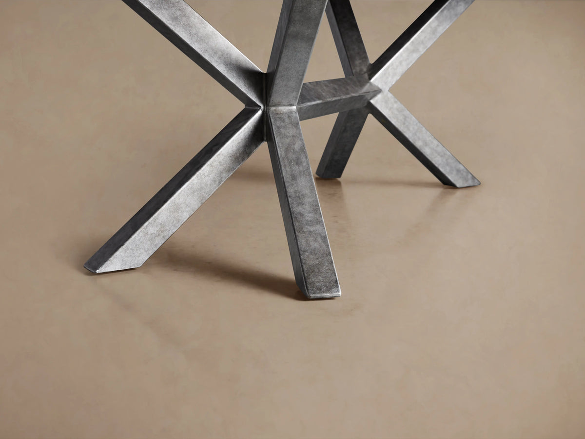Petra Dining Table with a handcrafted petrified wood tabletop featuring natural textures, atop an X-shaped iron base with grey patina.