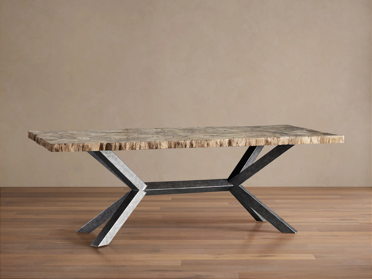 Petra Dining Table's artisan-finished iron base with an antiqued, dark grey patina shown in close-up against a neutral background.