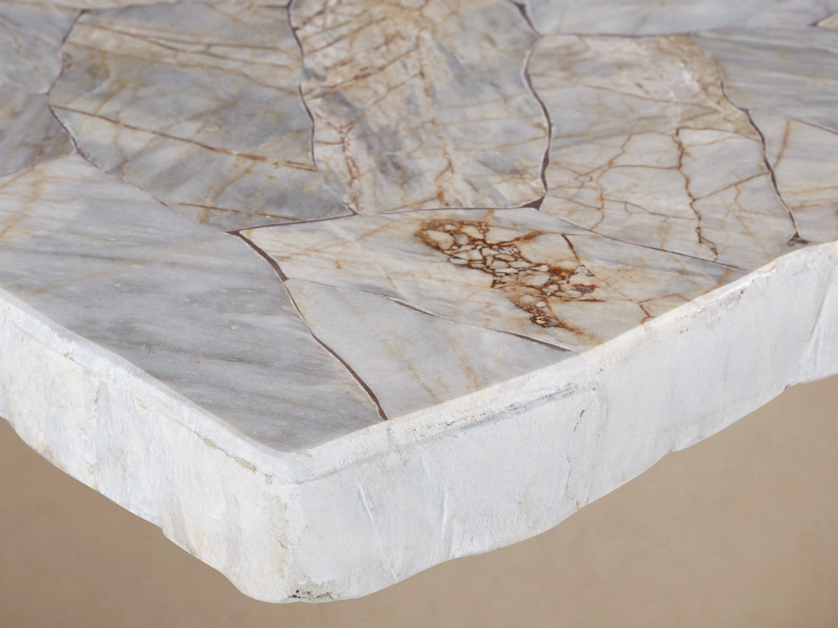Petra Dining Table with a handcrafted stone top and artisan-finished iron base in dark grey patina, set on wooden floor.