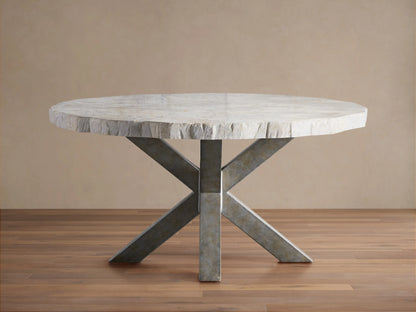 Round dining table with petrified wood top and textured surface, supported by an X-shaped iron base with dark grey patina, on wood floor.