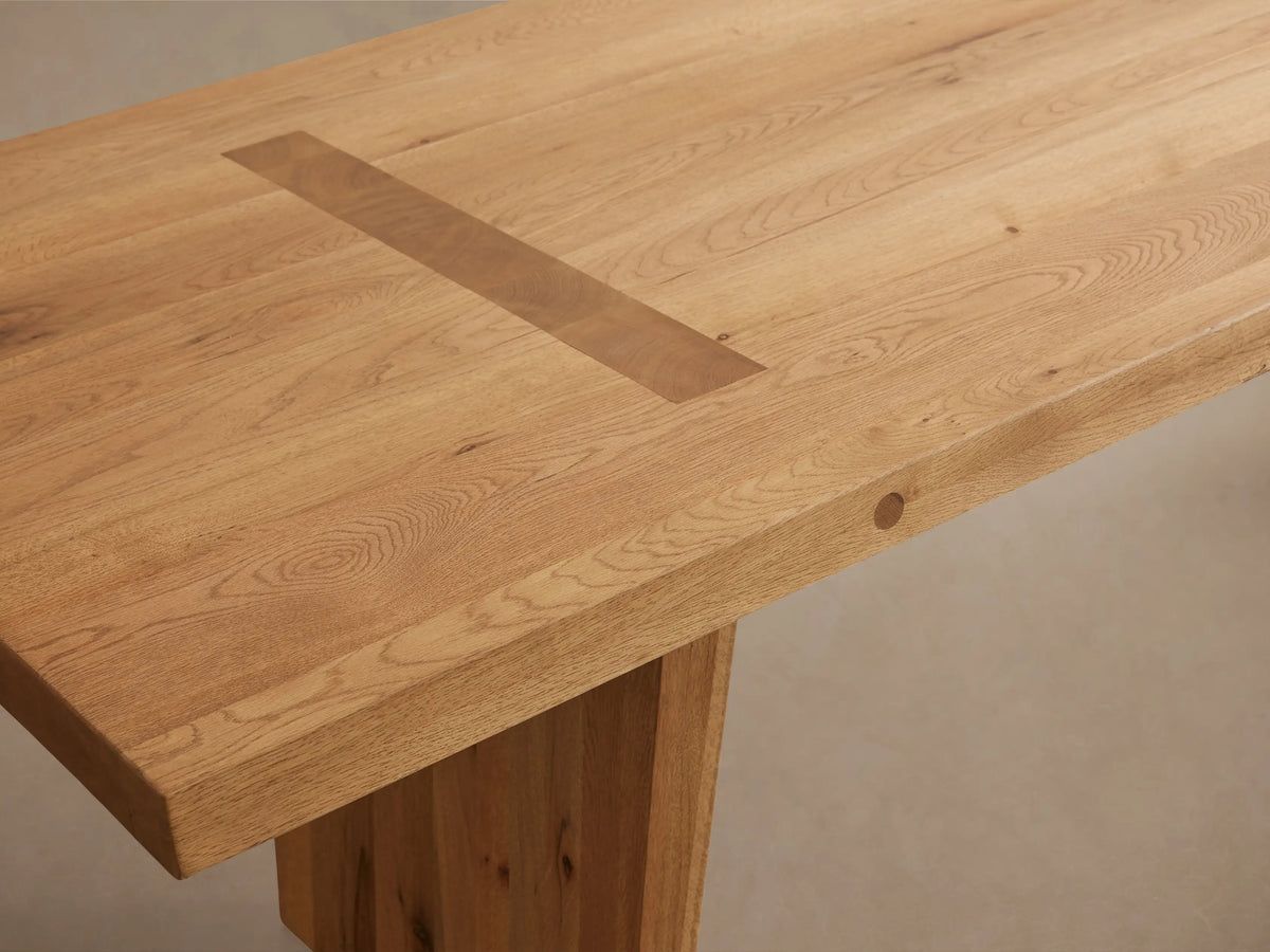 Panta Dining Table made of Romanian red oak wood, showcasing a simple, sleek design with angled legs and visible wood grain patterns.