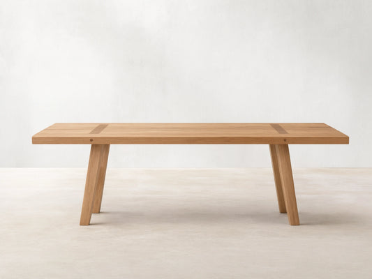Panta Dining Table made of Romanian red oak wood, showing natural grain patterns, rectangular top, and angled legs on wooden floor.