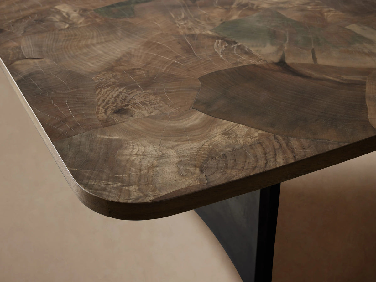 Polanco Dining Table. Dark, mottled wood top with rounded corners, supported by two weathered dark steel panel legs.