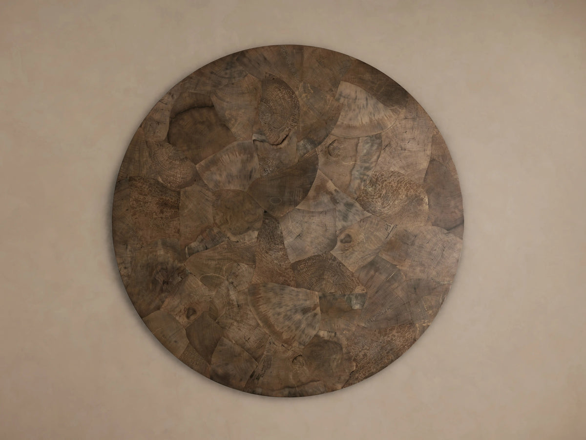 Polanco Round Dining Table: Overhead view of a textured round tabletop, made from dark brown, oyster-cut wood fragments.