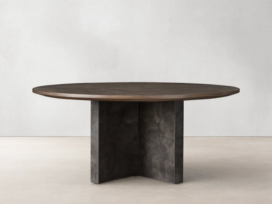 Polanco Round Dining Table with a textured dark wood top and weathered gray steel cross base, on a light wood floor.