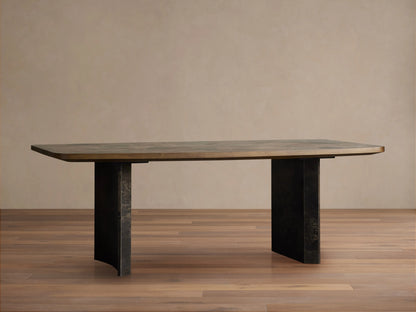 Polanco Dining Table with a mottled dark brown wooden top and two weathered dark metal, curved pedestal legs on a wooden floor.