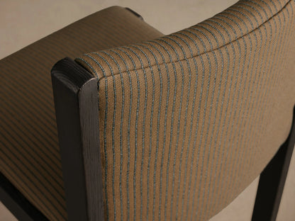 Paradiso Dining Chair, front view. Dark oak wood frame with tan upholstered seat and curved backrest, featuring thin black vertical stripes.