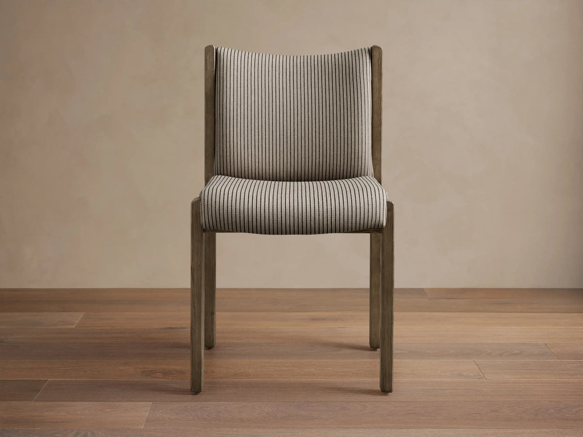 View of multiple Paradiso Dining Chairs with natural oak wood frames and light beige striped upholstery, arranged around a dining table.