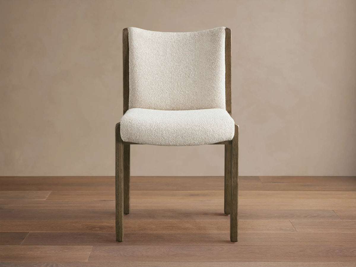Interior view of Paradiso Dining Chair with light oak wood frame and beige striped upholstery, placed at an oval dining table.
