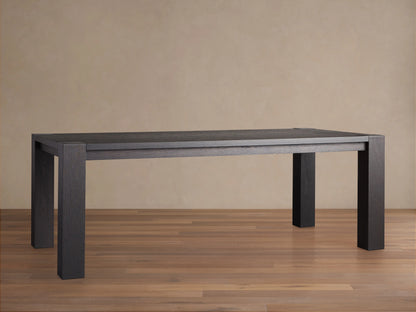 Parsons Dining Table crafted from dark Romanian oak wood with a rectangular top and thick rectangular legs, set on wooden floor.