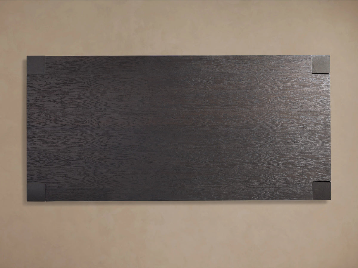 A close-up of the Parsons Dining Table's corner showing its dark oak wood texture and subtle sheen from the lacquer finish.