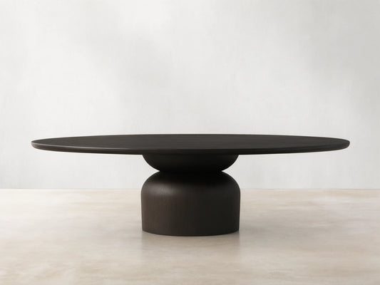 Dark wood Perth Oval Dining Table with an oval top and a sturdy, rounded pedestal base, resting on a wooden floor.